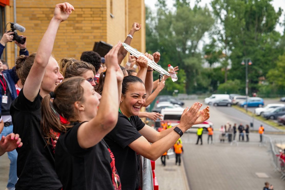 Gruppe junger Menschen feiert mit Freude und Begeisterung, während sie einen Pokal halten und applaudieren.