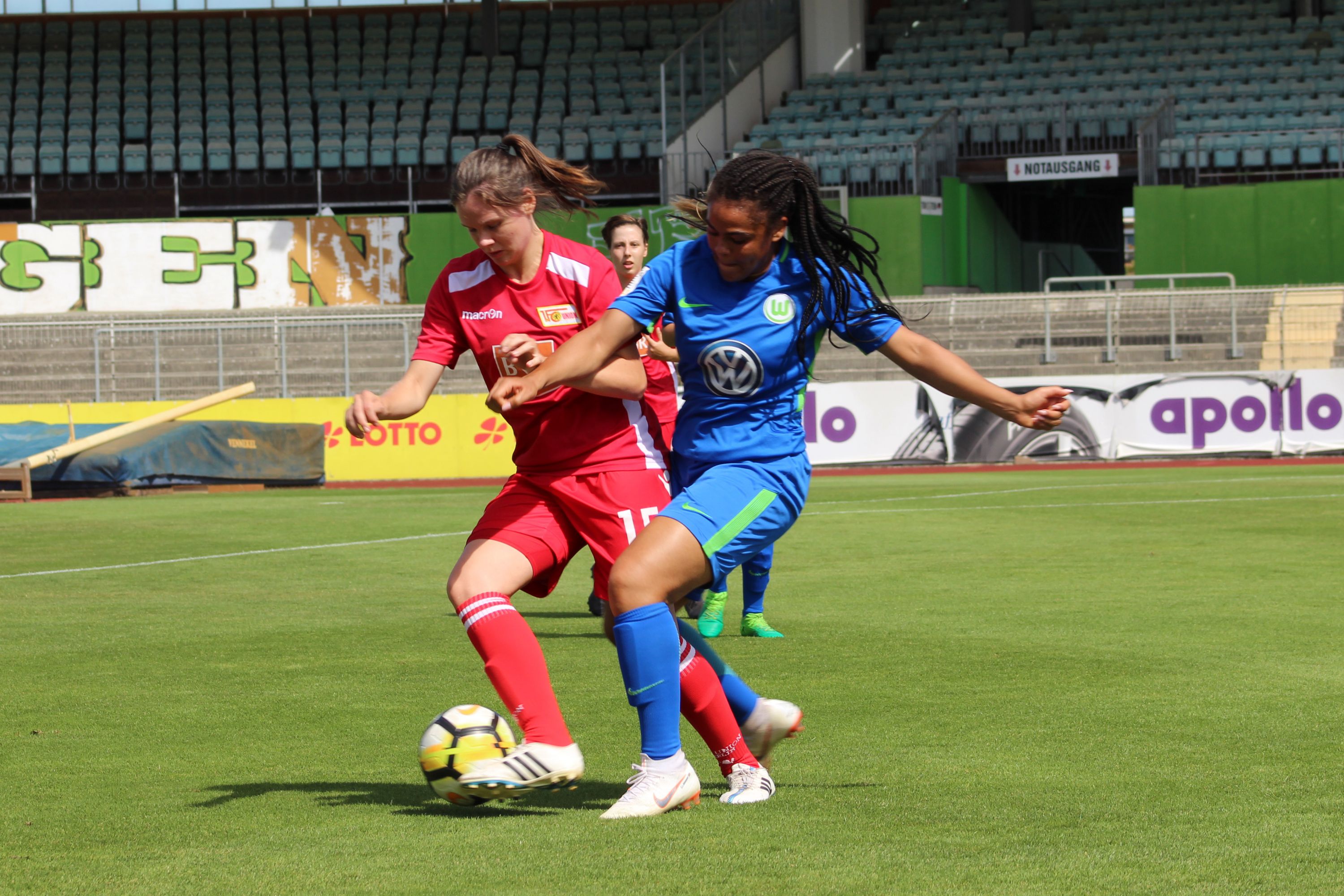 Zwei Fußballspielerinnen spielen auf einem Platz. Sie kämpfen um den Ball.