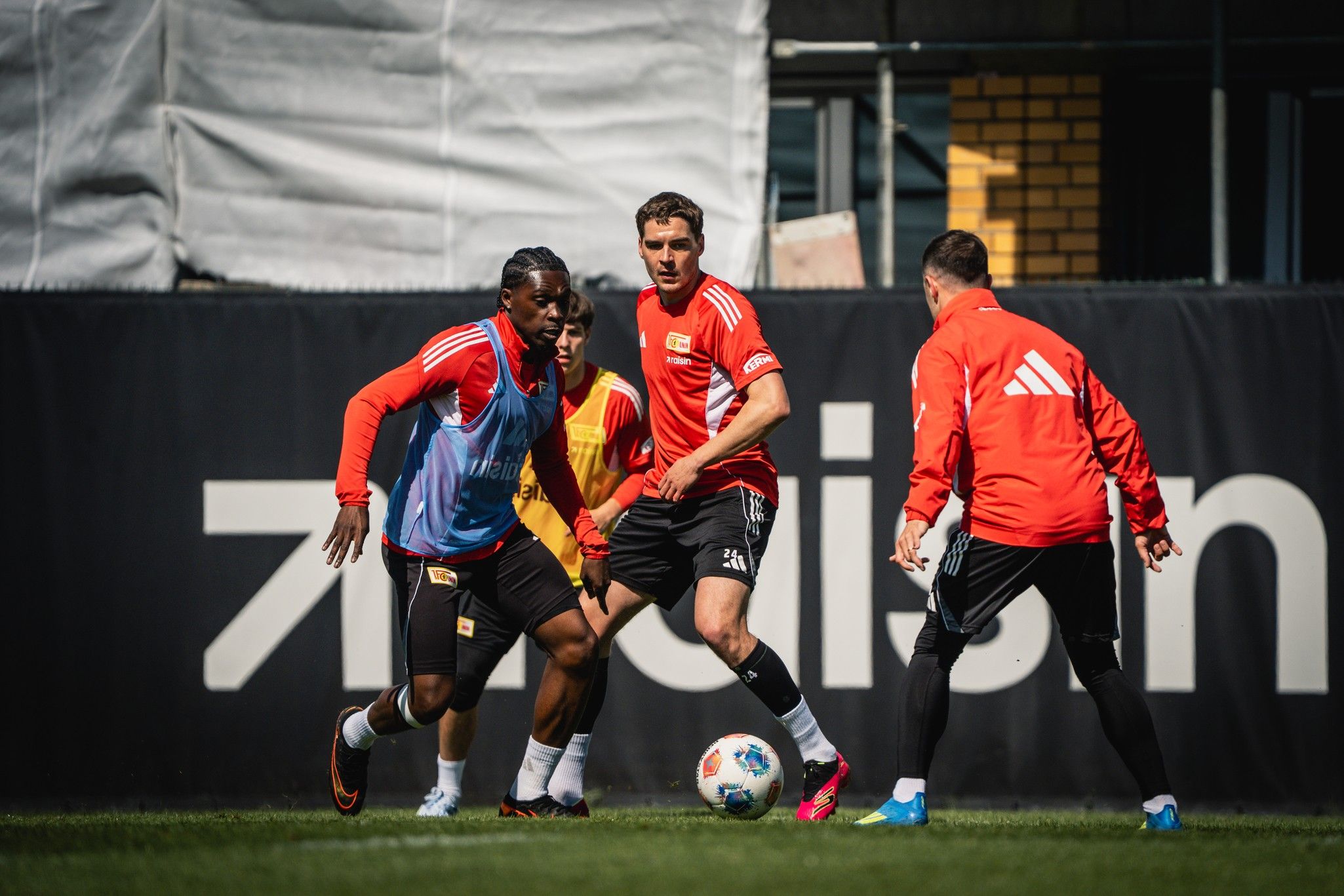 Vier Fußballspieler trainieren auf dem Platz, während ein Spieler den Ball führt.
