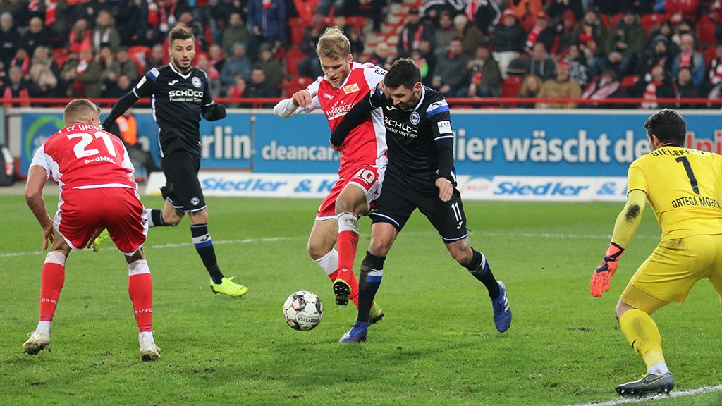 Game scene with several soccer players on the field, one player is dribbling while others try to defend against him.