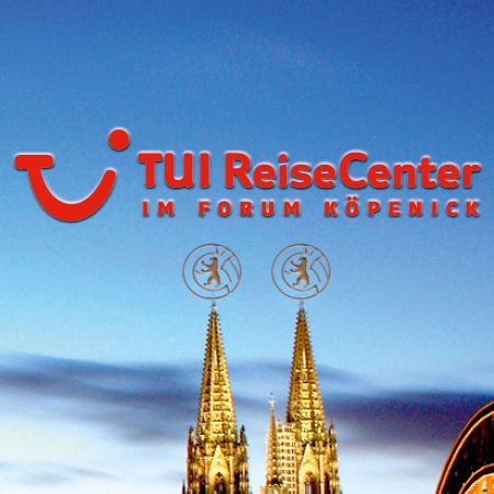 Logo des TUI ReiseCenters im Forum Köpenick, mit zwei markanten Türmen im Hintergrund und einem klaren blauen Himmel.