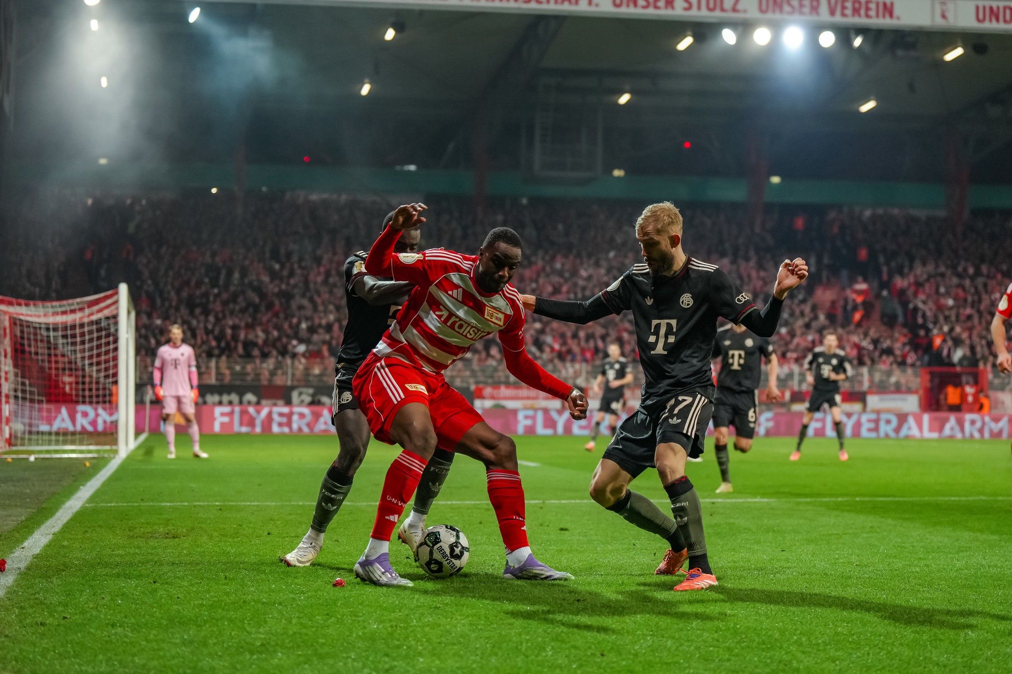 Spielszene im Fußball mit Spielern von Union Berlin und Bayern München, die um den Ball kämpfen, im Stadion.