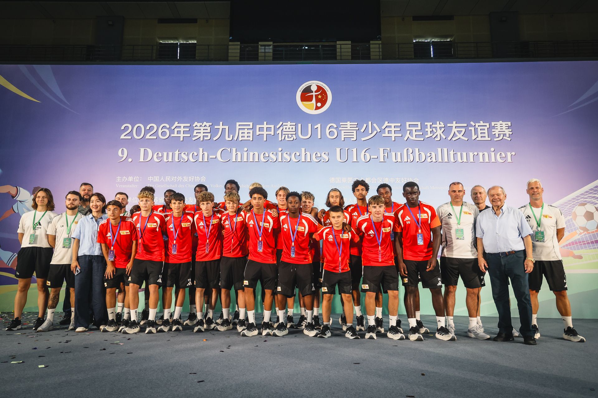 Eine Gruppe von Jugendlichen in roten Trikots posiert für ein Gruppenphoto nach einem Fußballturnier.