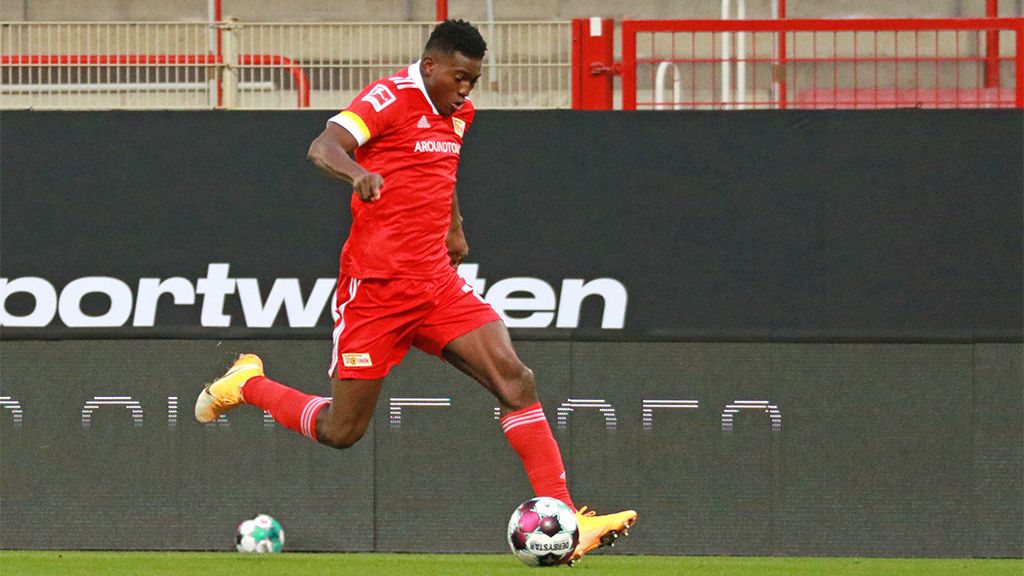 A soccer player in a red jersey kicks the ball on a field.