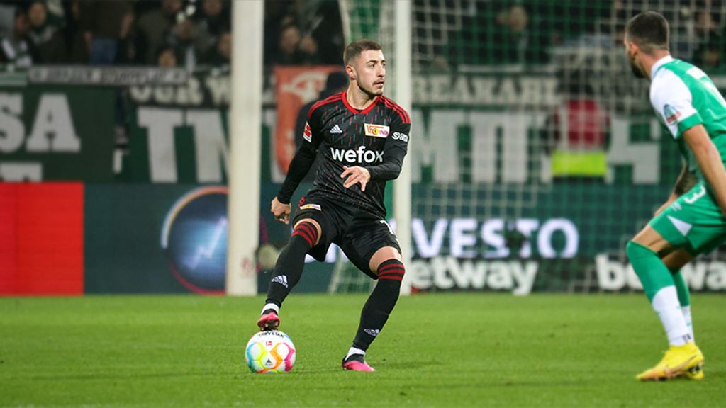 Ein Fußballspieler in schwarzer Torwartkleidung mit Wefox-Logo dribbelt den Ball auf einem Fußballfeld.