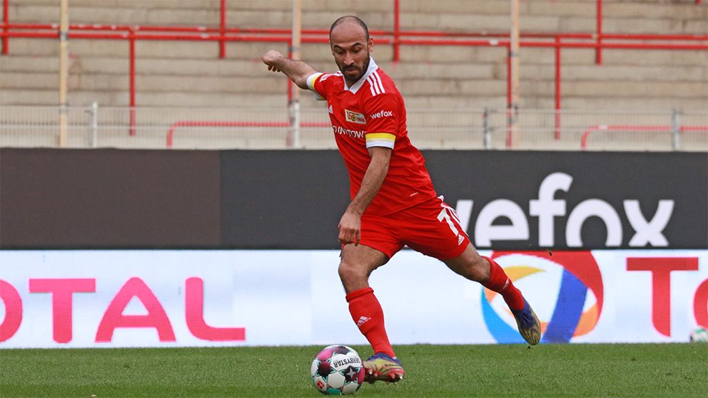 A soccer player in a red jersey takes a shot on the field.