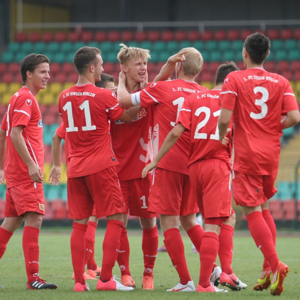 Spieler des 1. FC Union Berlin feiern einen Erfolg in roten Trikots auf dem Spielfeld.