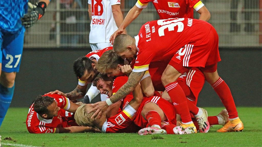 Players celebrate a goal on the field, huddled together in a cheering group.