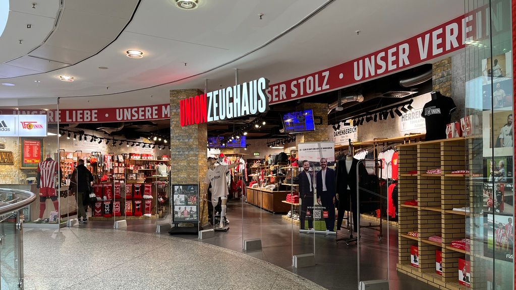 Ein Sportgeschäft mit Merchandise-Artikeln und Bekleidung, dekoriert mit den Farben und Logos eines Sportvereins.