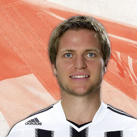 Ein lächelnder Fußballspieler trägt ein weißes Trikot mit schwarzen Streifen und steht vor einem grafischen, orangefarbenen Hintergrund.