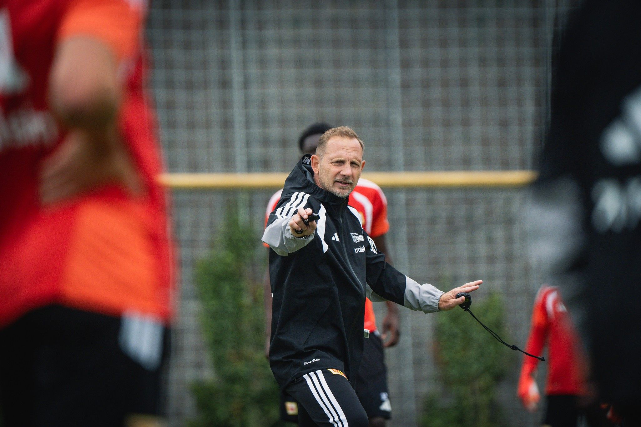 Ein Fußballtrainer leitet ein Training und gibt Anweisungen an seine Spieler in einem Trainingsgelände.