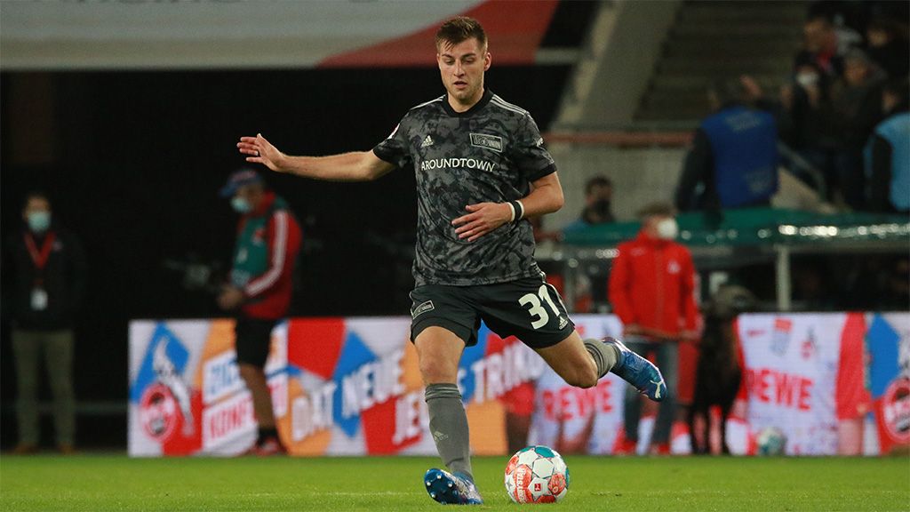 A soccer player in a gray jersey with number 31 is dribbling the ball on the field.
