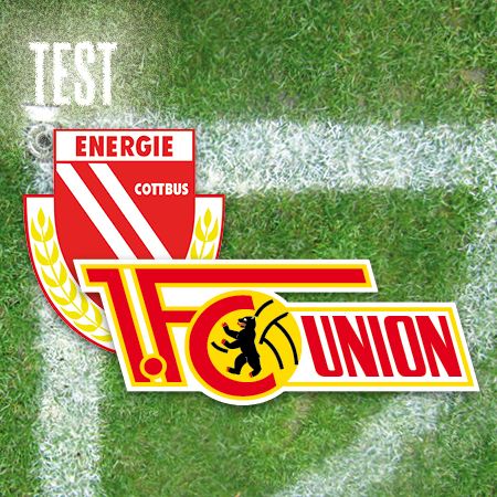 Logo von Energie Cottbus und FC Union auf einem Rasenfeld mit Testbeschriftung.