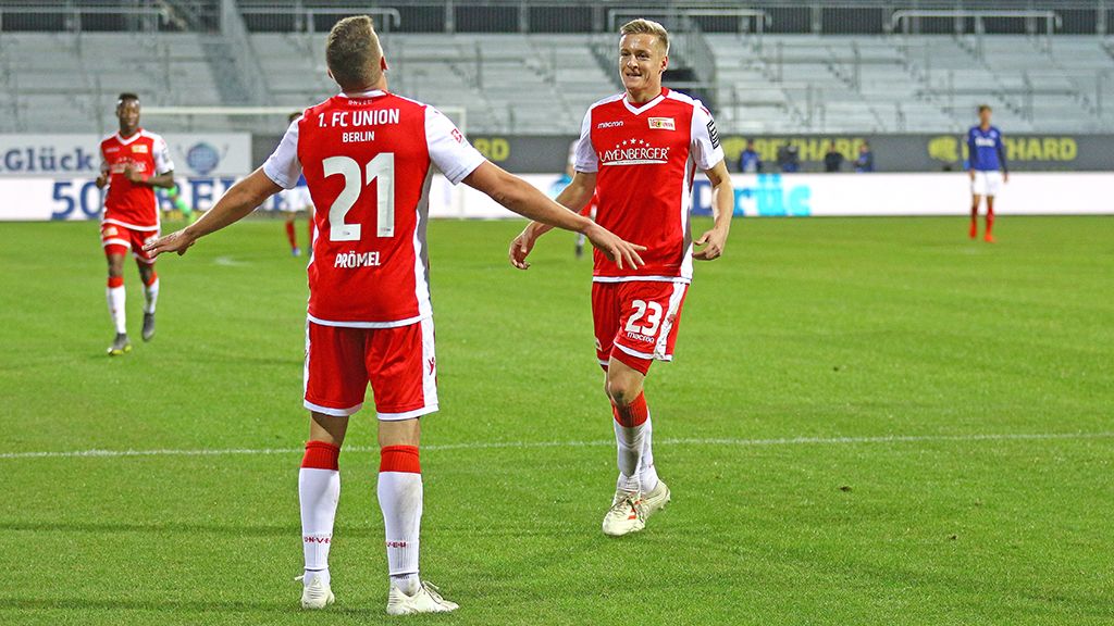 Zwei Fußballspieler des 1. FC Union Berlin feiern einen Treffer auf dem Spielfeld.