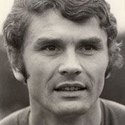 Ein Porträt eines Mannes mit kurzem, gewelltem Haar und einem freundlichen Gesichtsausdruck, aufgenommen in Schwarz-Weiß.