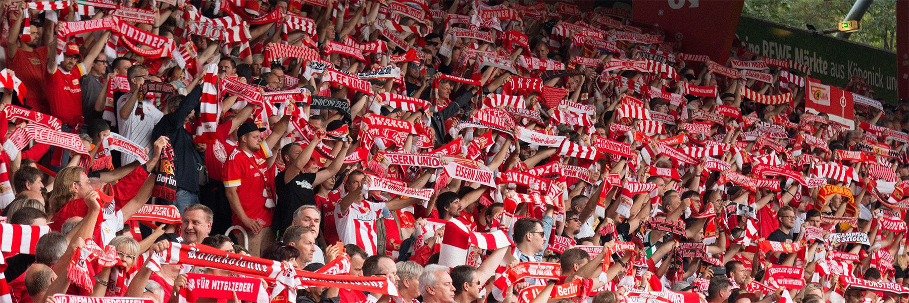 A cheering crowd with red and white scarves in a stadium.