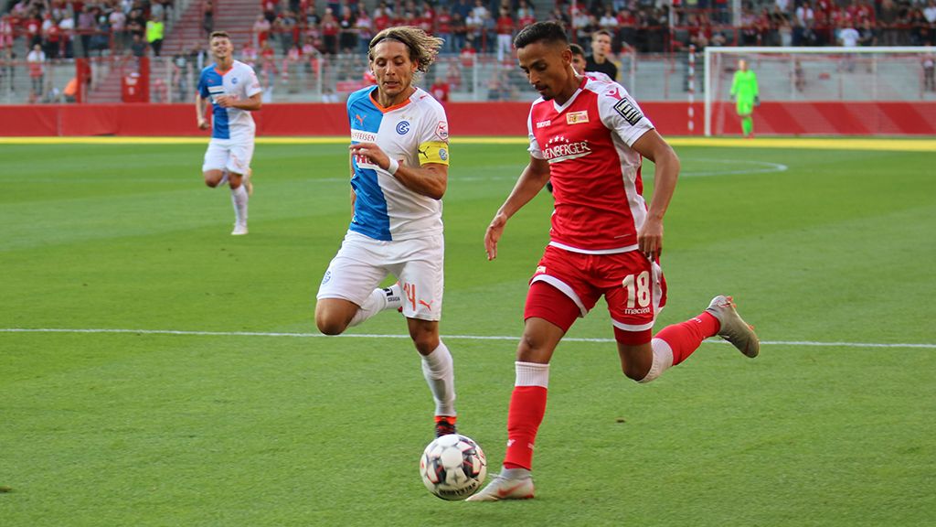 Spielszene im Fußball: Ein Spieler mit der Nummer 18 sprintet mit dem Ball, während ein Gegenspieler ihn verfolgt.