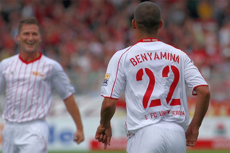 Zwei Fußballspieler auf dem Platz, einer trägt das Trikot mit dem Namen "BENYAMINA" und der Nummer 22.