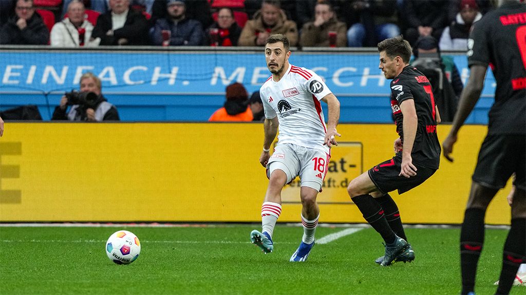 Game scene in football with a player in white controlling the ball while an opposing player in black approaches.