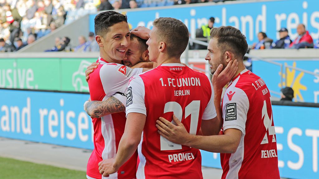 Players of 1. FC Union Berlin celebrate a goal in a stadium. Emotional embrace between teammates.