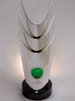 Eine stilisierte, moderne Trophäe mit drei geschwungenen Elementen und einer grünen Basis.