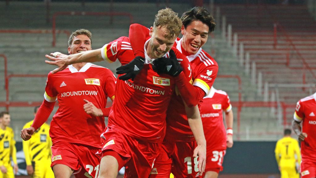 Spieler des 1. FC Union Berlin feiern einen Torerfolg in rot-weißen Trikots auf dem Spielfeld.