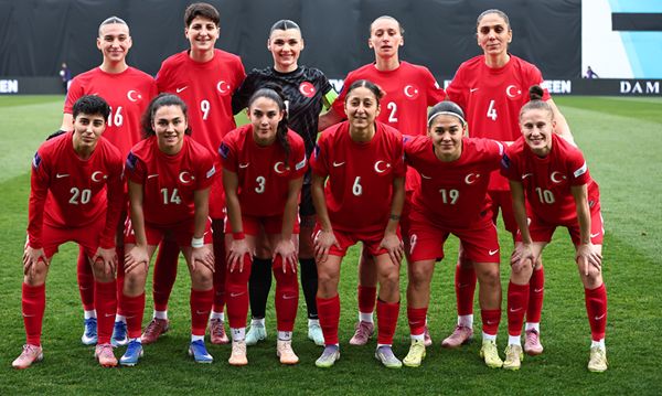 Eine Fußballmannschaft in roten Trikots steht auf dem Spielfeld, aufgereiht in zwei Reihen.