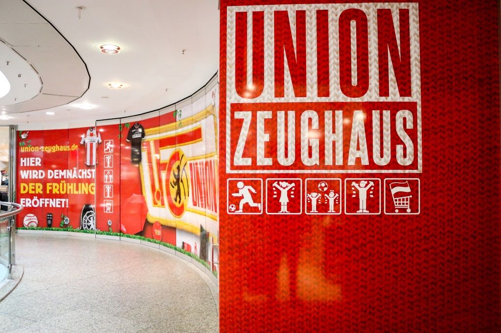 Wand mit rotem Hintergrund und der Aufschrift "UNION ZEUGHAUS" sowie Symbolen und dem Text "HIER WIRD DEMNÄCHST DER FRÜHLING ERÖFFNET!"