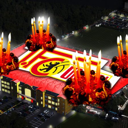 Ein Stadiondach mit einem Logo, umgeben von brennenden Kerzen und einer stimmungsvollen, nächtlichen Umgebung.