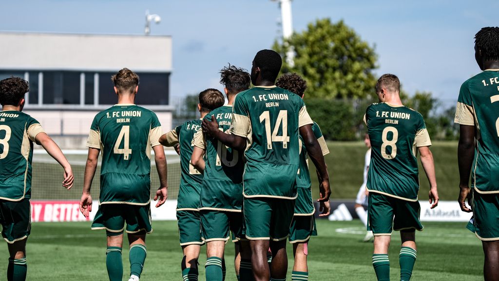 Eine Gruppe von Fußballspielern des 1. FC Union Berlin in grünen Trikots läuft auf einem Trainingsplatz.