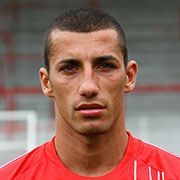 Ein junger Spieler in rotem Trikot mit kurzen Haaren, schaut direkt in die Kamera.