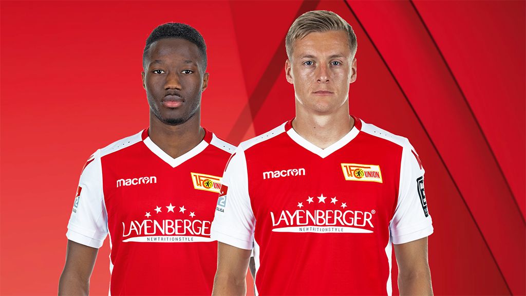 Zwei Fußballspieler in rot-weißen Trikots vor einem roten Hintergrund.