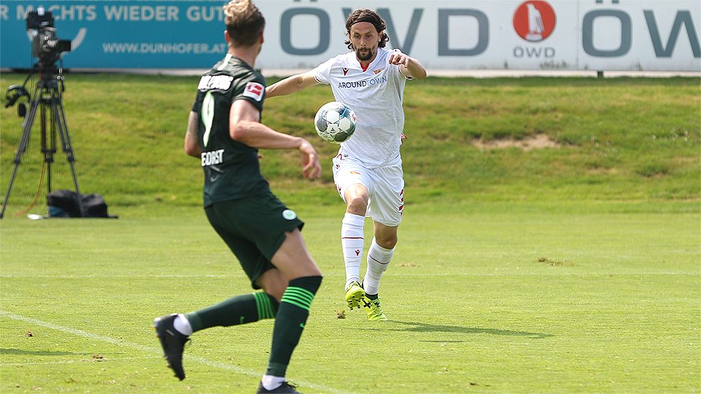 Football player passes the ball during a practice match on a sports field.