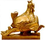 Eine goldfarbene Statue einer Katze, die auf einem Huhn sitzt, auf einem Sockel aus Holz.