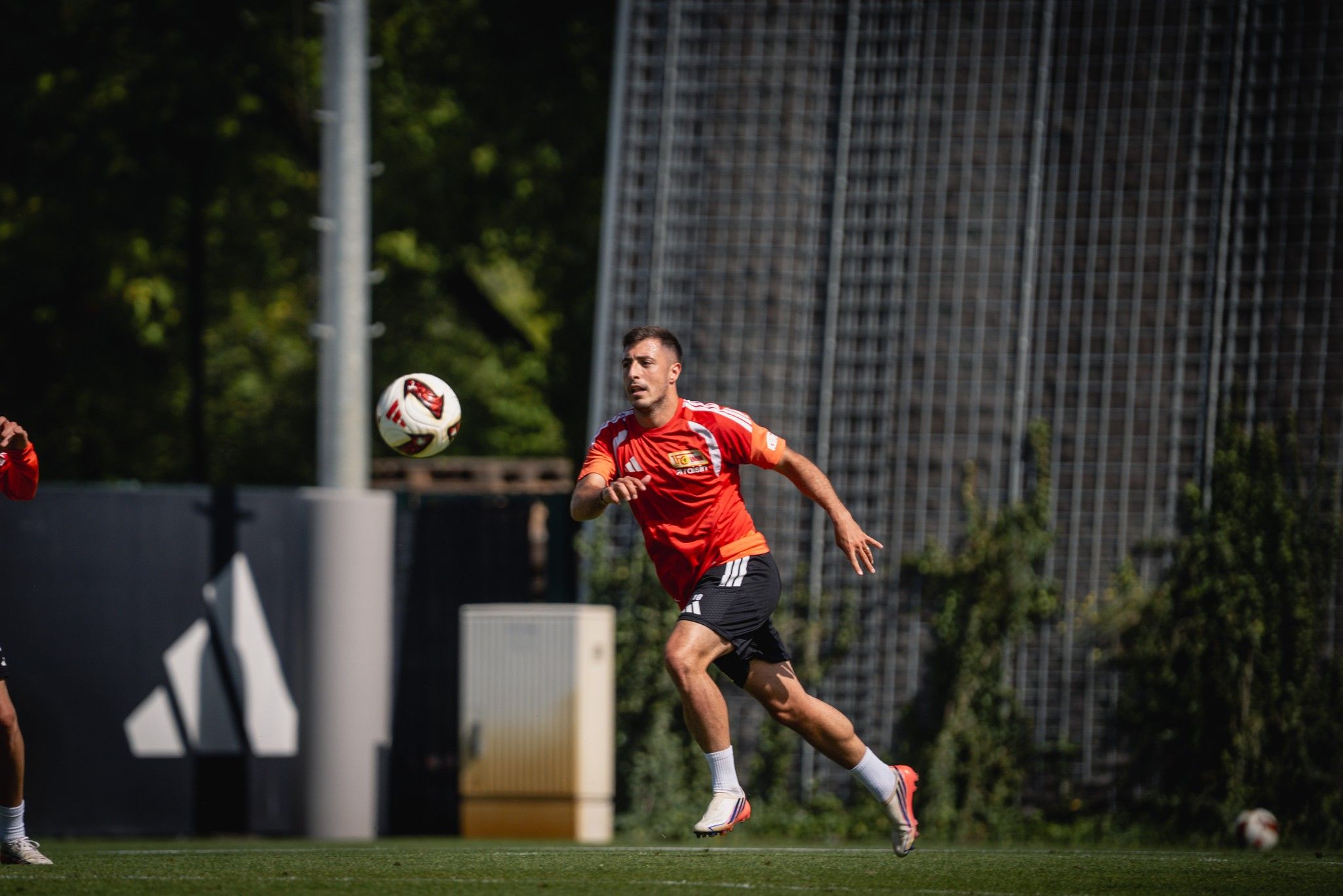 Ein Fußballspieler in orangefarbener Trainingskleidung sprintet während einer Übungseinheit.
