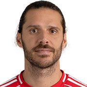 Portrait eines Mannes mit langen Haaren und Bart, der ein rotes Fußballtrikot trägt.