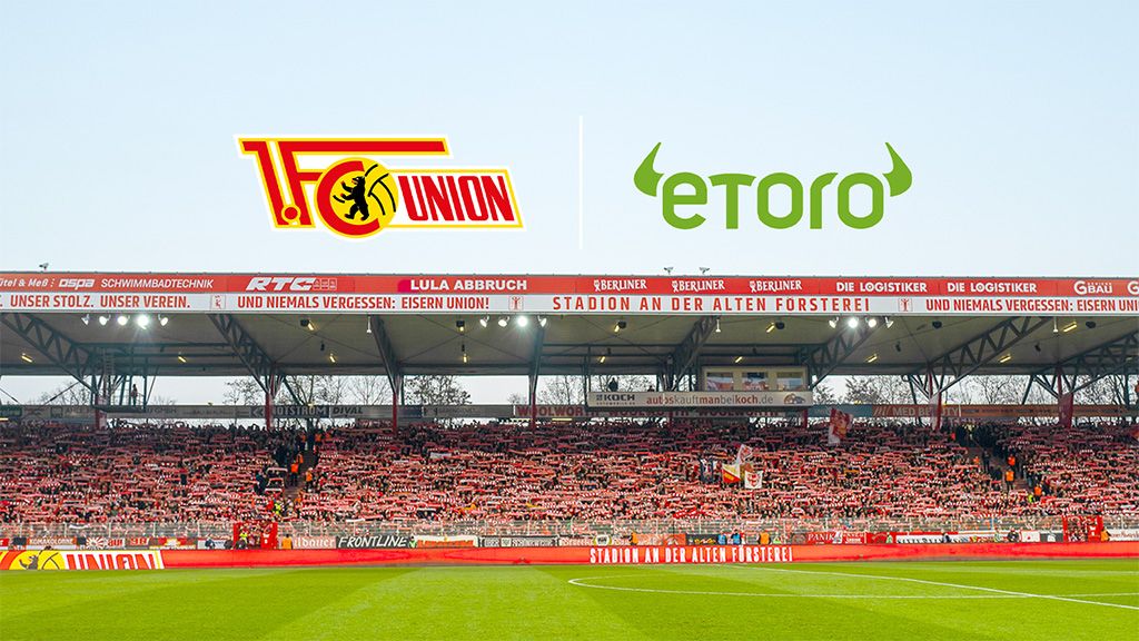 The stadium of 1. FC Union Berlin with a fan mosaic and sponsor logos in the background.