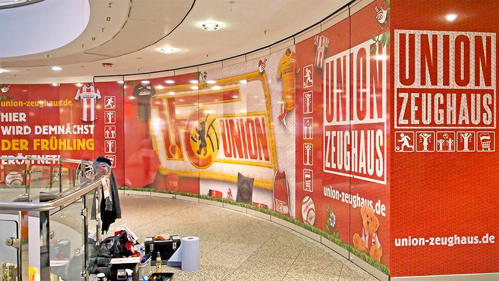 Wandgestaltung in einem Geschäft mit dem Schriftzug "UNION ZEUGHAUS" und verschiedenen Fußball-Symbolen und -Accessoires.