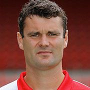 Porträt eines sportlich gekleideten Mannes mit kurzem, dunkelbraunem Haar, der in die Kamera schaut.