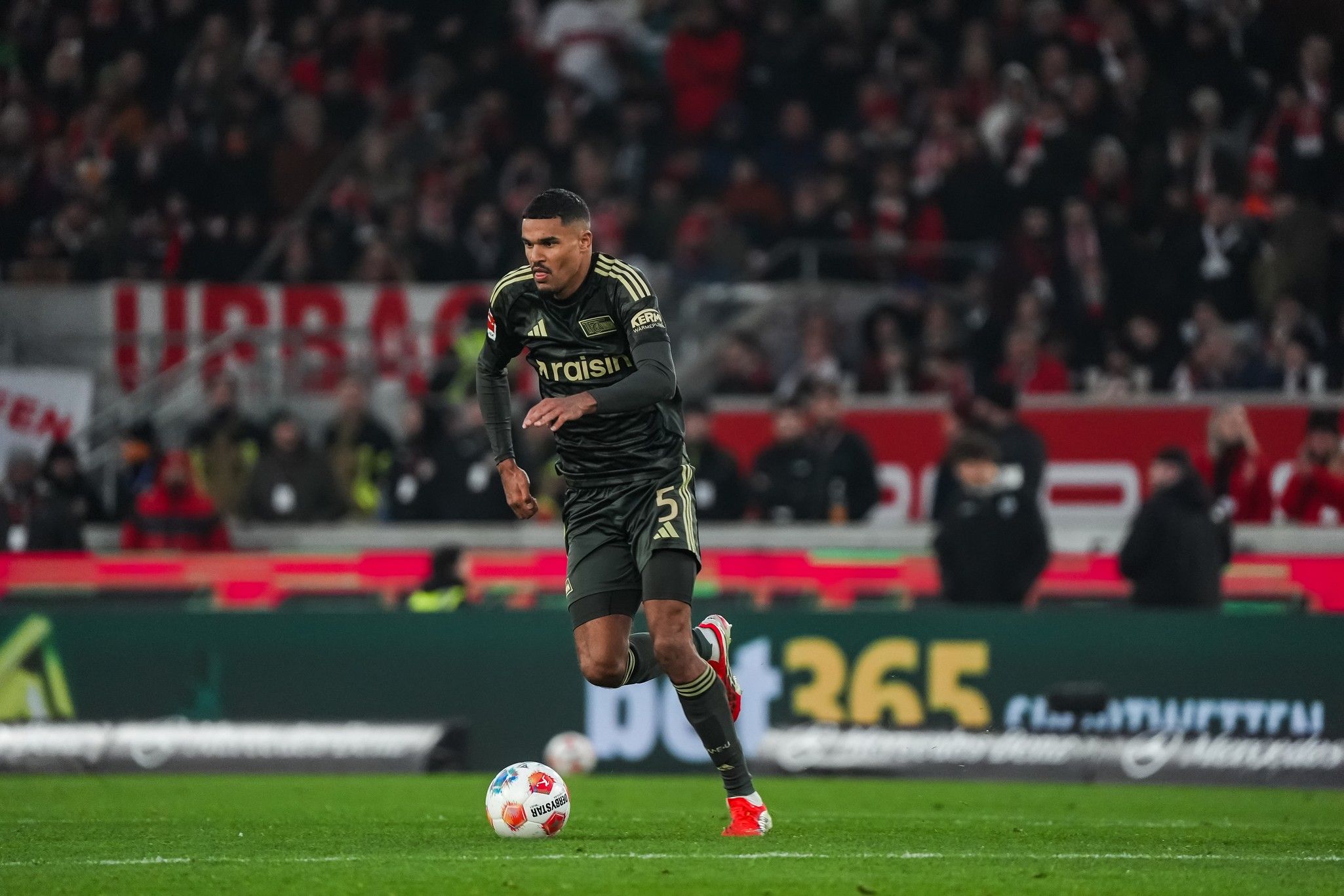 Ein Fußballspieler in schwarzem Trikot sprintet über das Spielfeld während eines Spiels.