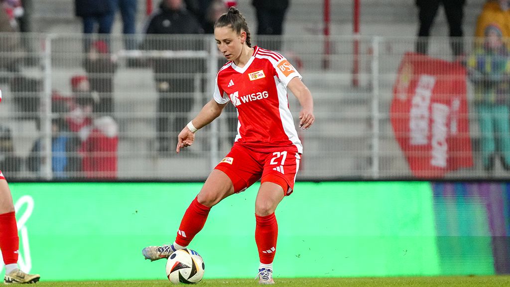 Spielerin in rotem Trikot mit der Nummer 21, die den Ball während eines Fußballspiels kontrolliert.