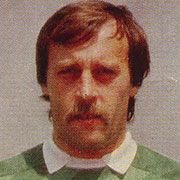 Ein sportlicher Mann mit einem Schnurrbart trägt ein grünes Trikot und schaut direkt in die Kamera.