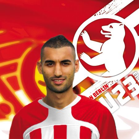 Ein Fußballspieler in einem roten und weißen Trikot, vor einem grafischen Hintergrund mit einem Bären und dem Schriftzug „U23“.