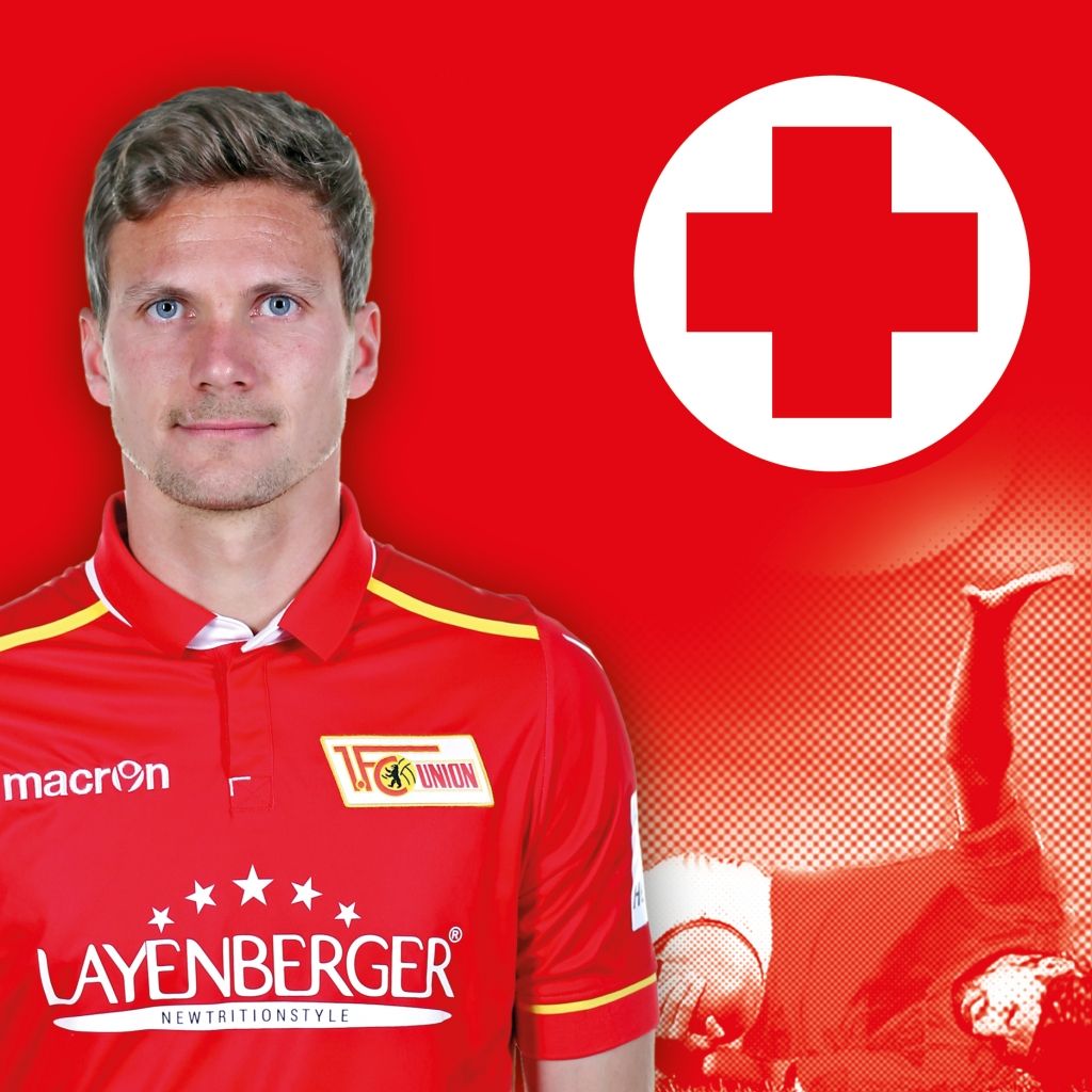 Spieler im roten Trikot von Union Berlin mit einem Kreuzsymbol im Hintergrund.