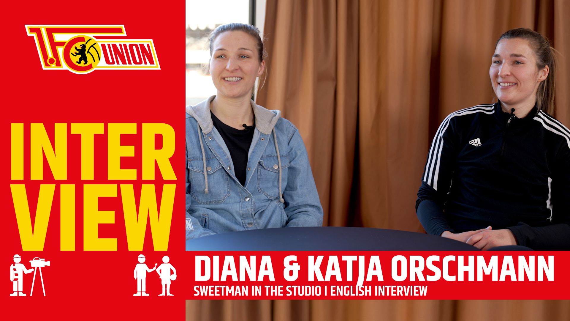 Diana and Katja Orschmann are smiling at a table in an interview room, surrounded by brown curtains.