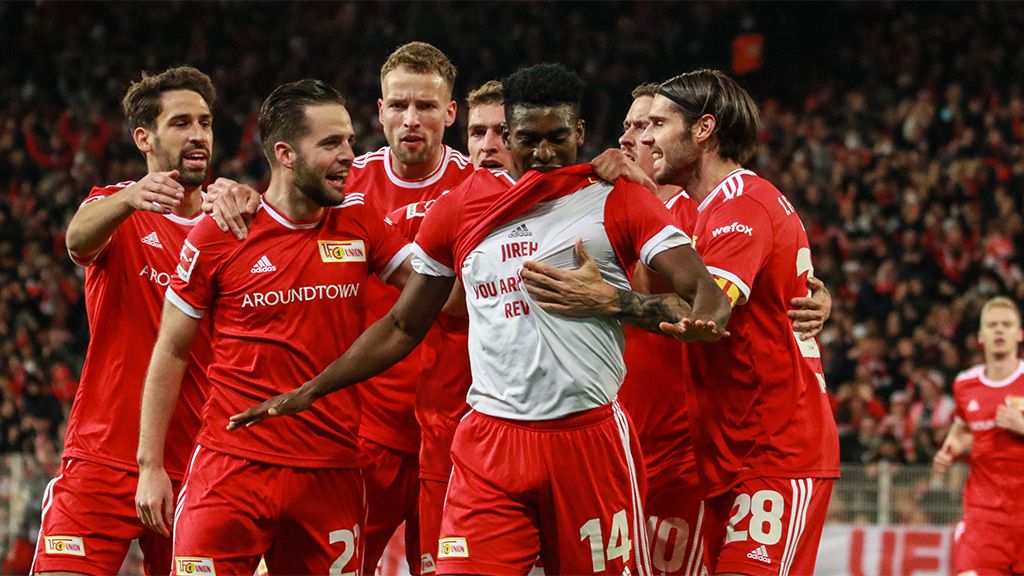 Spieler der Fußballmannschaft Union Berlin feiern einen Torerfolg in einem Stadion mit jubelndem Publikum.