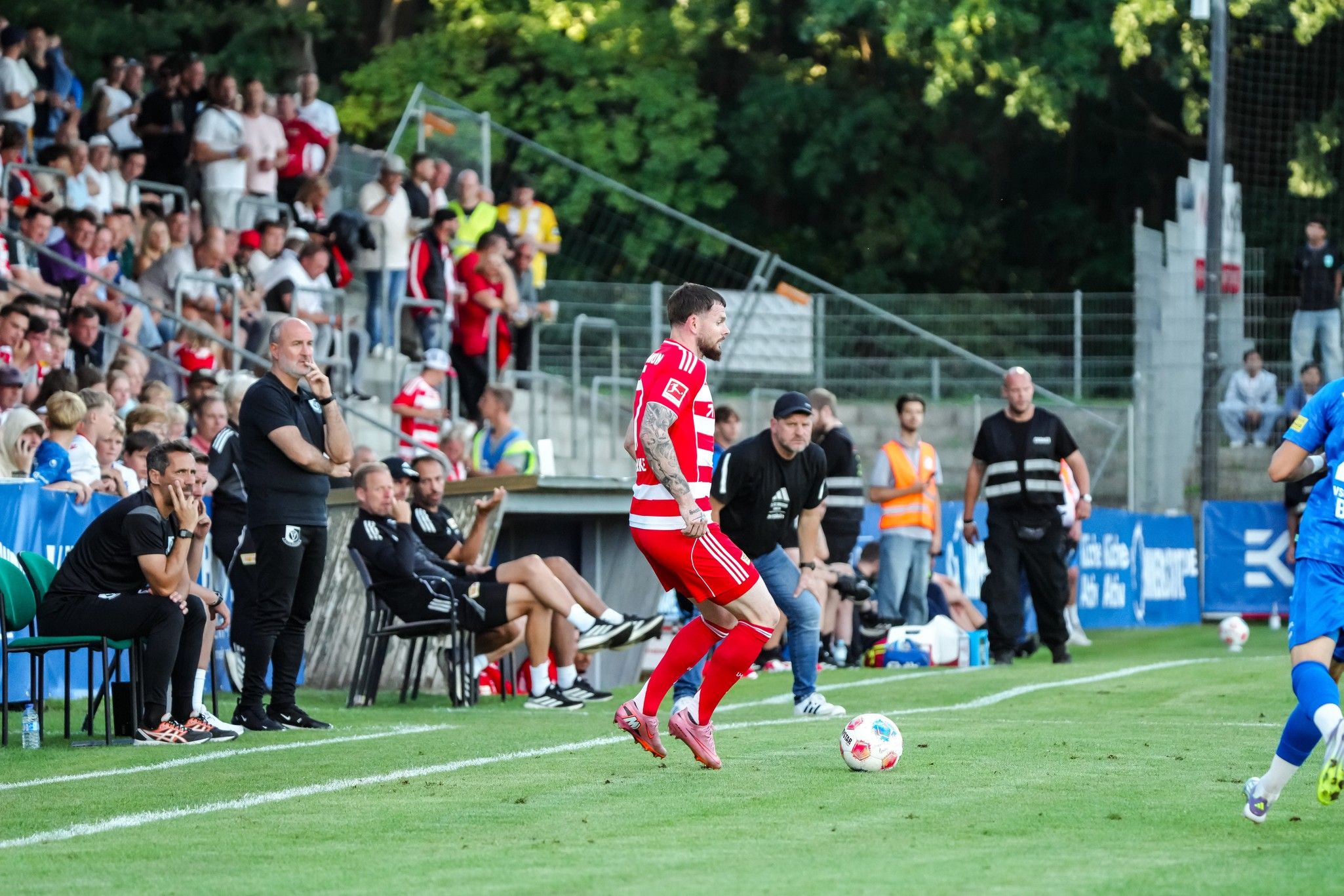 Ein Fußballspieler in rot-weißer Uniform bereitet sich darauf vor, den Ball während eines Spiels an der Seitenlinie zu spielen.
