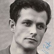 Schwarz-weiß Porträt eines jungen Mannes mit kurzem, dunklem Haar und einem nachdenklichen Ausdruck. Handschriftliche Signatur unten rechts.