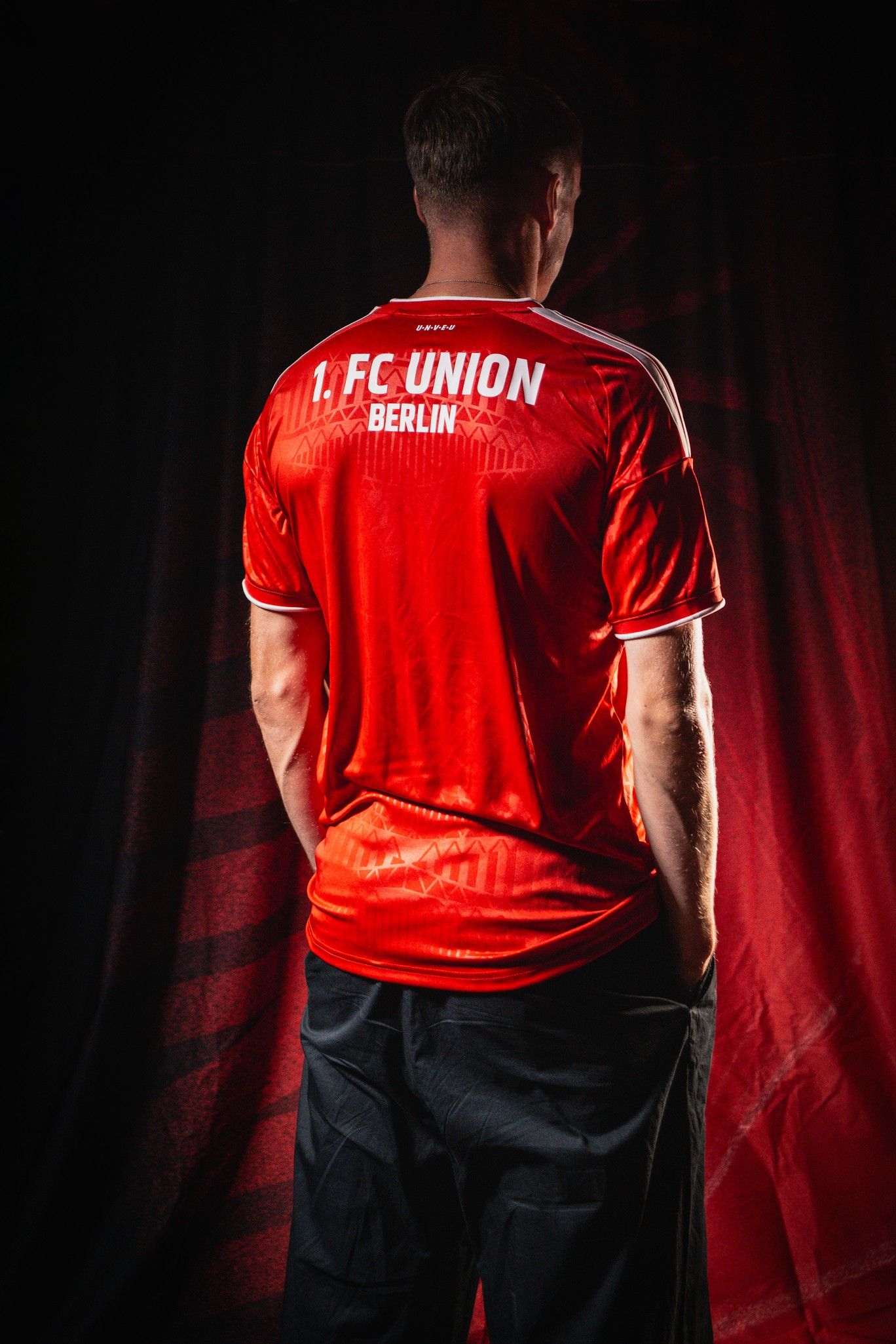 Ein Mann steht mit dem Rücken zur Kamera und trägt ein rotes Fußballtrikot mit der Aufschrift "1. FC UNION BERLIN".
