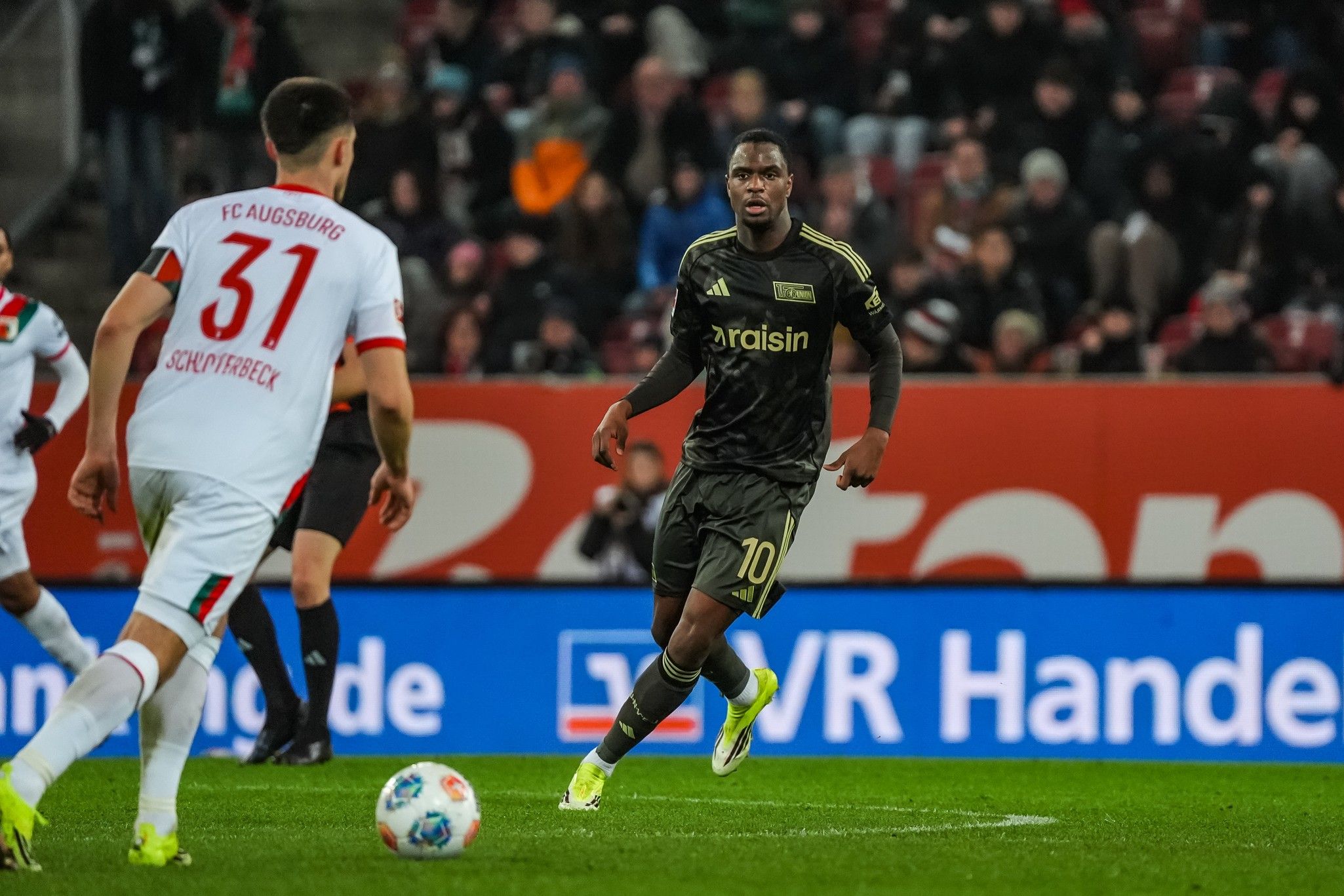 Ein Spieler in schwarzer Trikotnummer 10 dribbelt den Ball, während ein Gegner in weißem Trikot 31 ihn markiert.